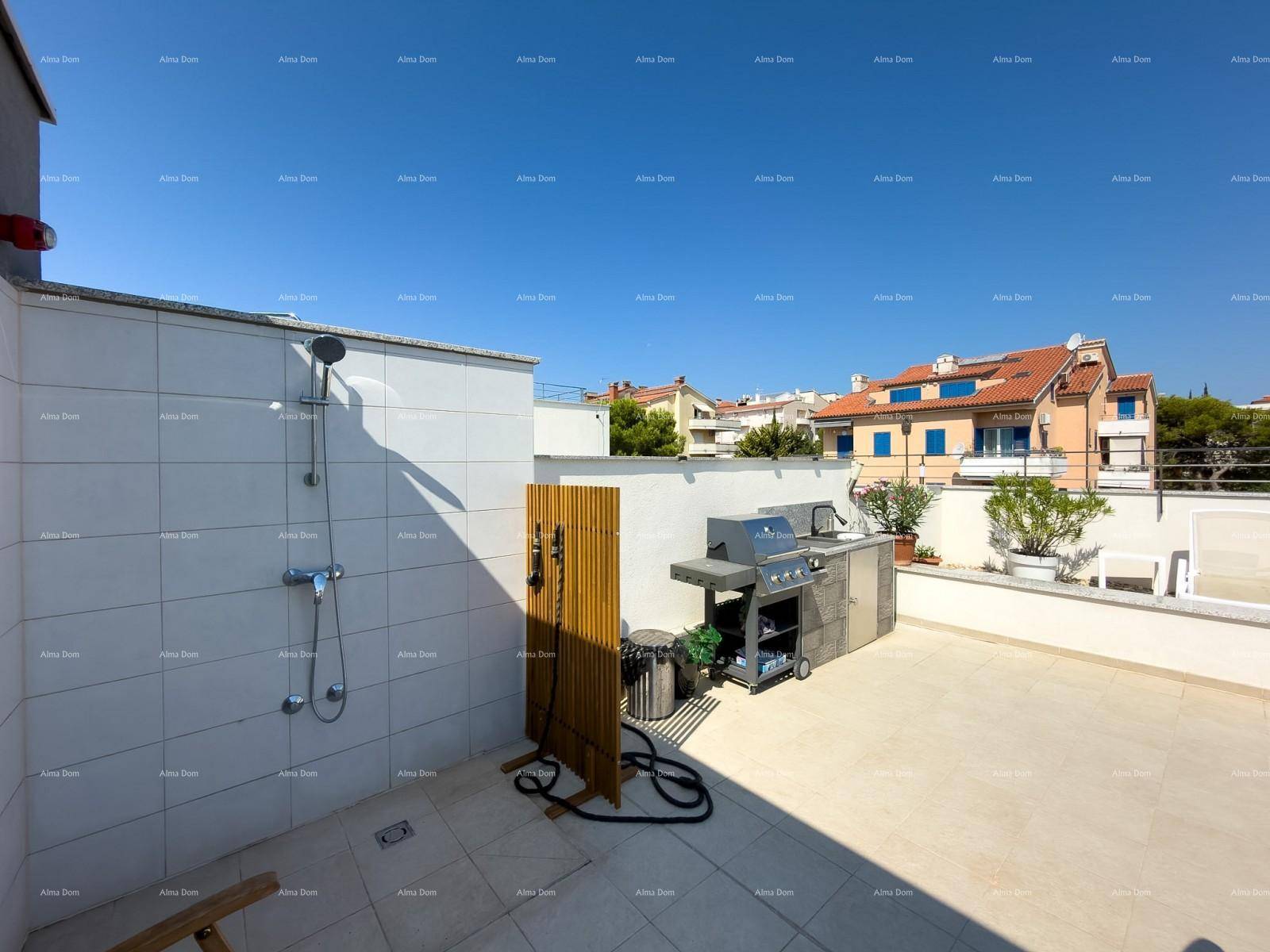 Geräumige Dachterrasse mit Außendusche und Grillbereich unter blauem Himmel.