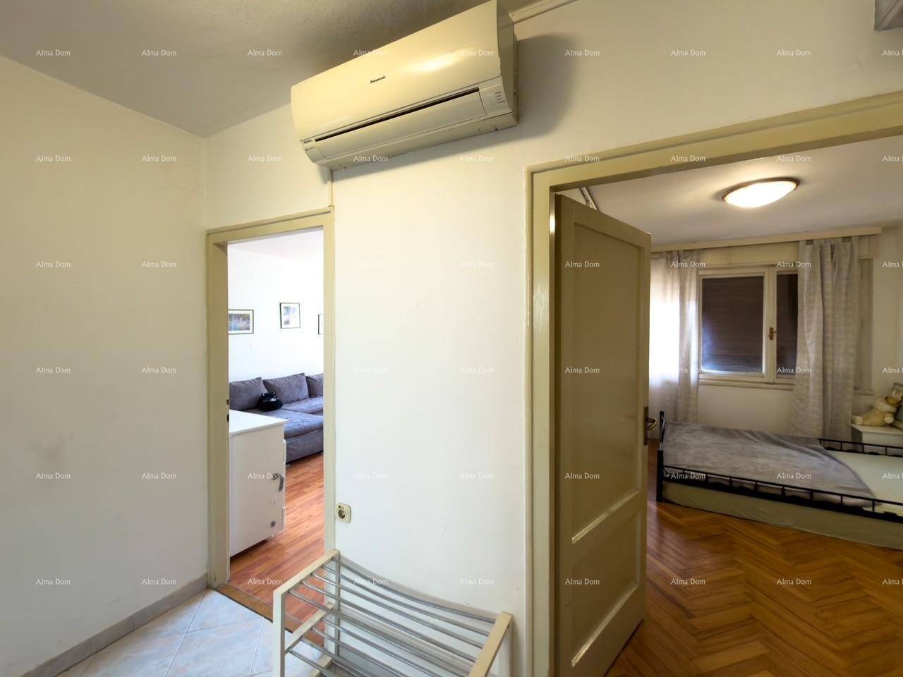 Flur mit Klimaanlage und Zugang zu einem Schlafzimmer mit Holzfußboden.