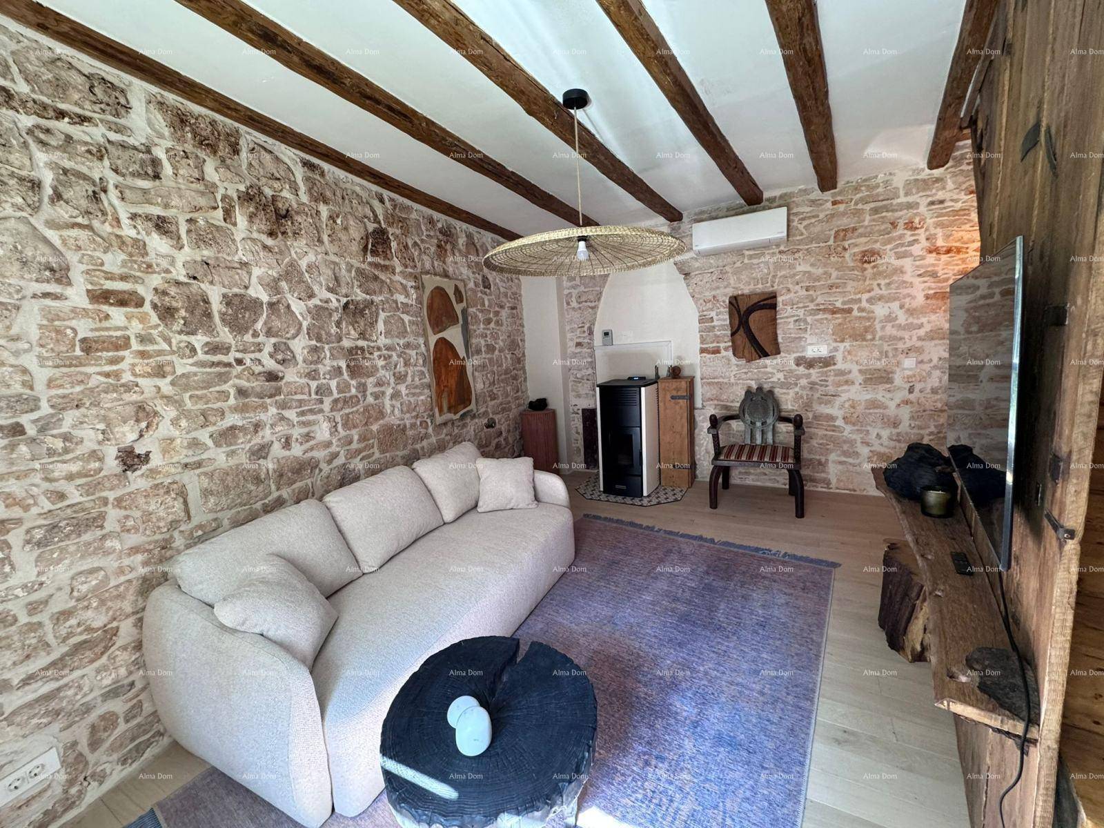 Gemütliches Wohnzimmer mit Steinwänden, Holzbalkendecke und modernem Sofa, mit Kaminofen.