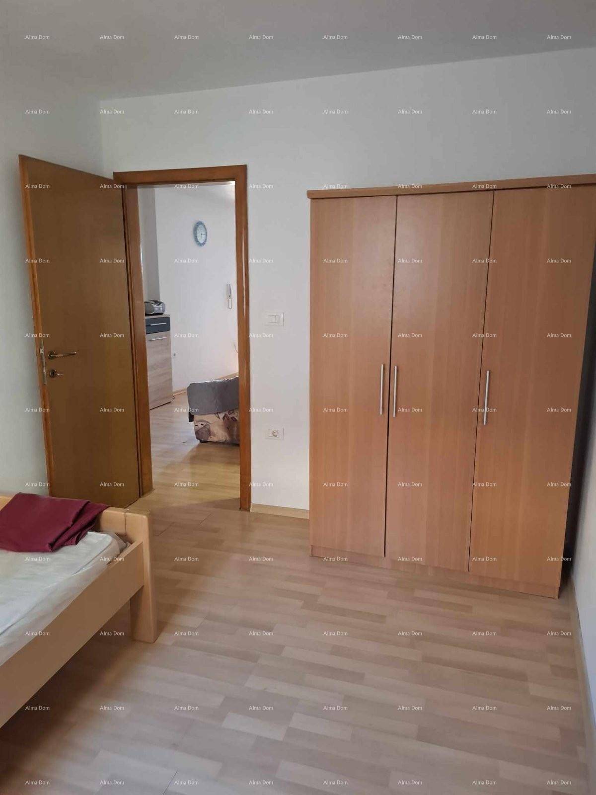 Schlafzimmer mit hellem Laminatboden und einem großen Holzschrank, Blick in einen weiteren Raum.