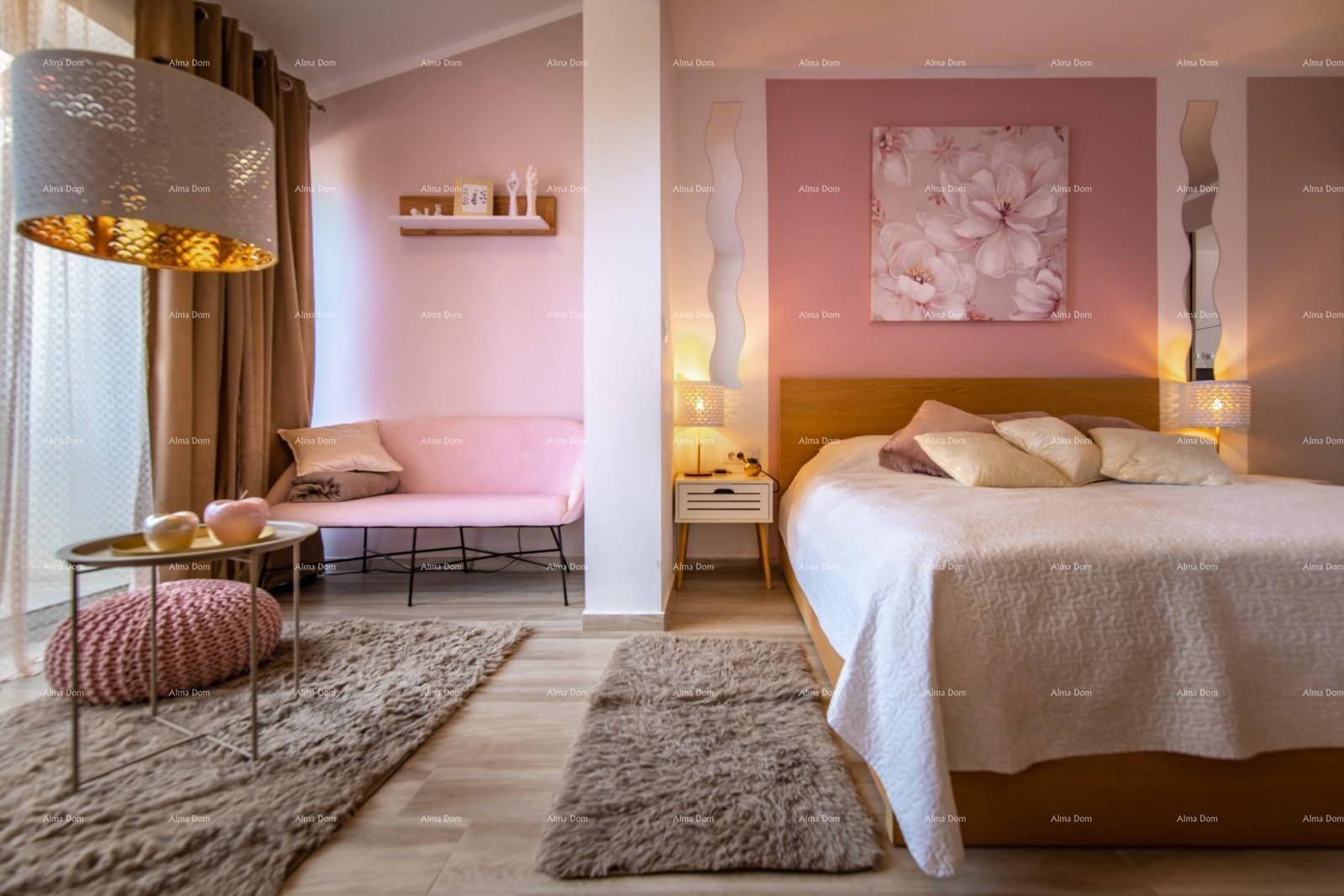 Helles Schlafzimmer mit einem großen Bett, einer gemütlichen Sitzecke und rosa Akzenten.