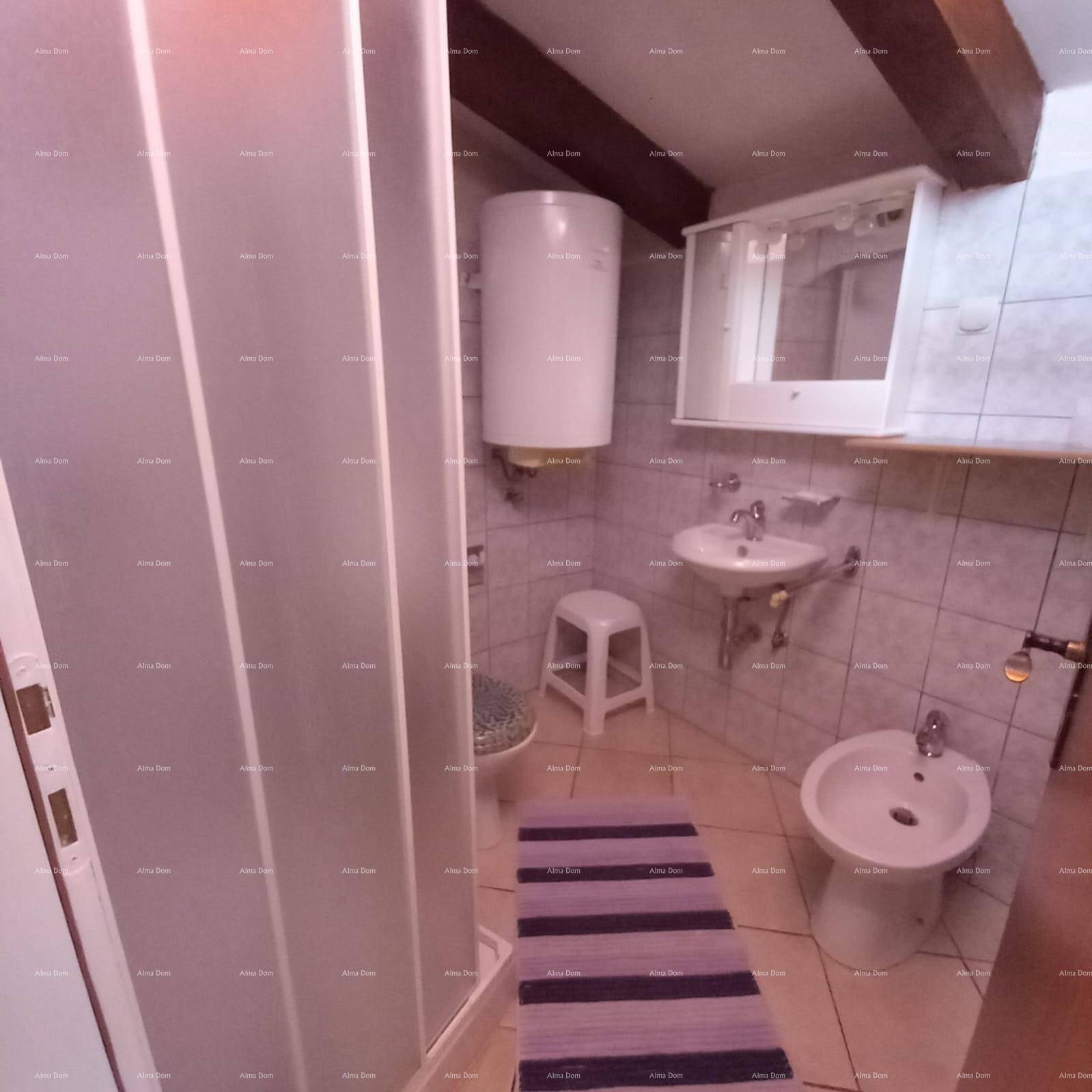 Badezimmer mit Duschkabine, Waschbecken, Bidet und Boiler, unter sichtbaren Holzbalken.