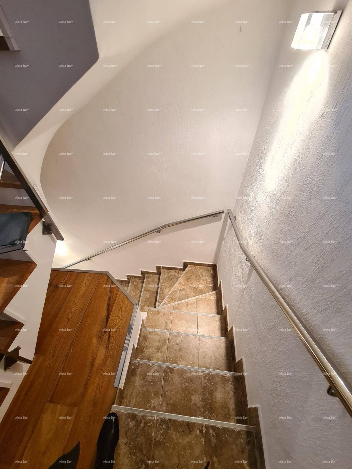 Blick von oben auf die geflieste Treppe mit modernem Metallgeländer, die nach unten führt.