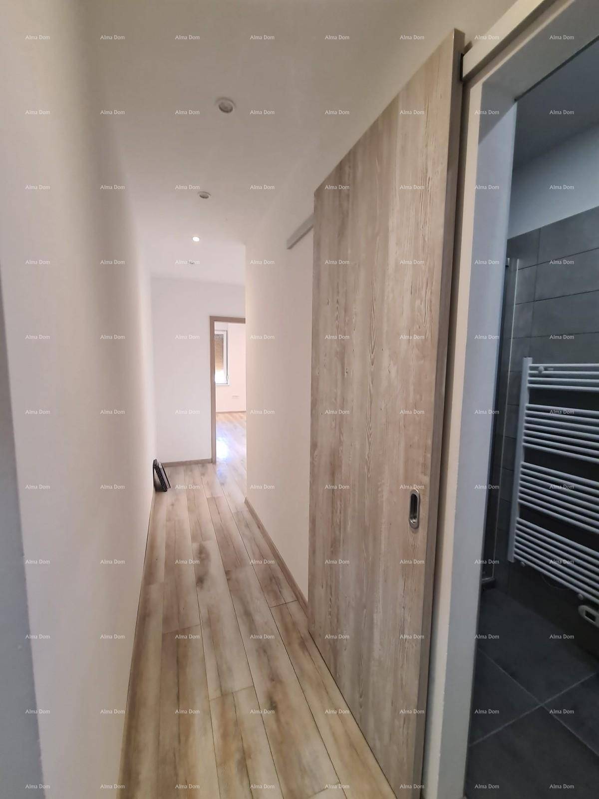 Heller Flur mit Holzoptik-Fliesenboden und einer modernen Schiebetür zum Badezimmer.