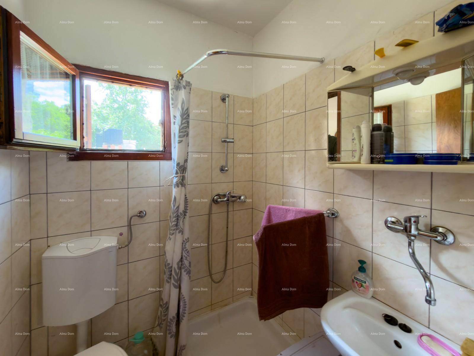 Helles Badezimmer mit Duschwanne, WC und Fenster, einfach und sauber gefliest.