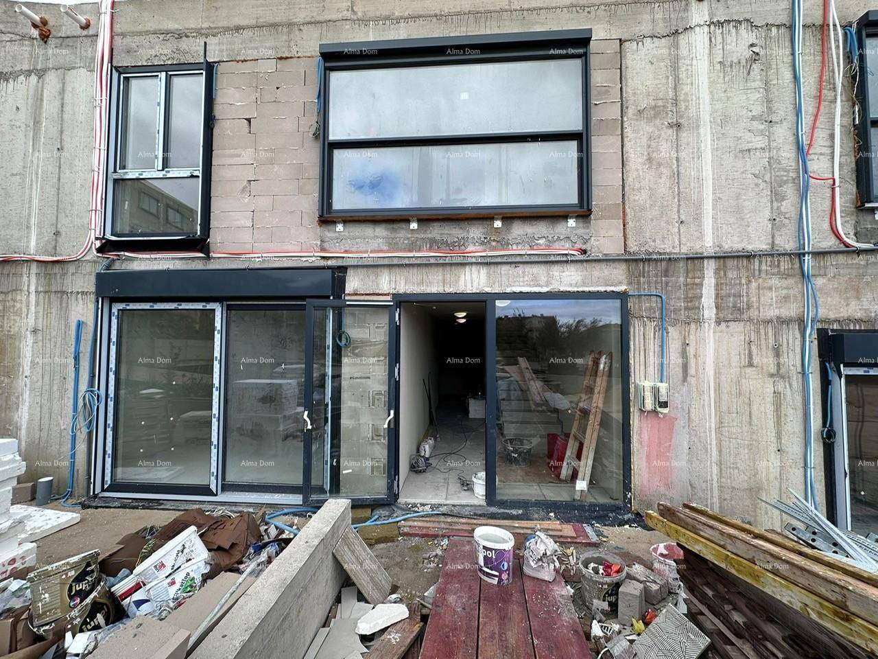 Nahaufnahme der Gebäudefassade mit Eingangsbereich und Fenstern, die sich noch im Bau befinden.