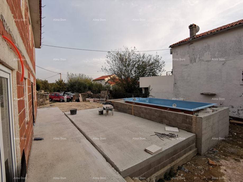 Baustelle mit einem im Bau befindlichen Pool und dem Rohbau eines Hauses im Hintergrund.