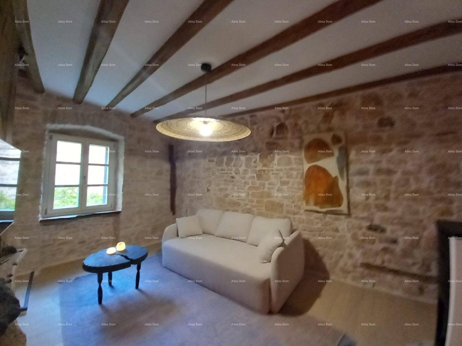 Gemütliches Wohnzimmer mit freiliegenden Steinwänden, Holzbalkendecke und modernem Sofa.