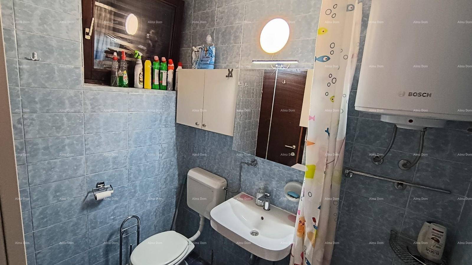 Badezimmer mit blauen Fliesen, Waschbecken, Spiegel und Warmwasserboiler.