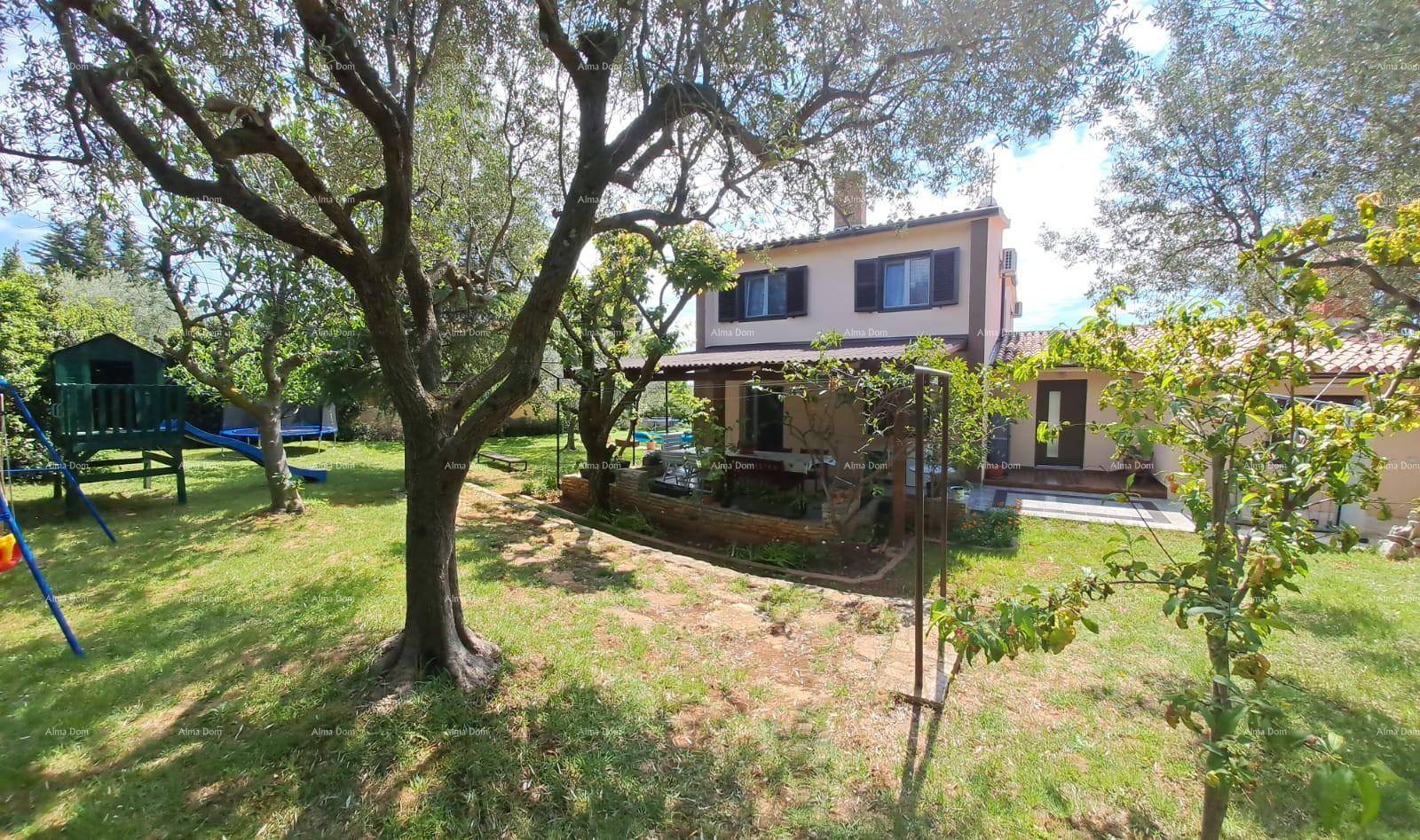 Rückansicht des Hauses mit überdachter Terrasse und weitläufigem Garten mit Bäumen.