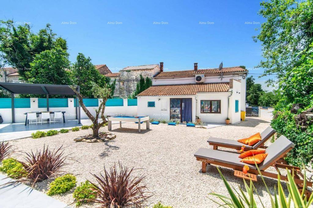 Außenbereich mit Kiesgarten, überdachtem Essbereich und einem Billardtisch neben dem Haus.