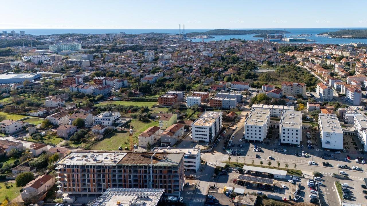 Weitläufige Luftaufnahme einer Stadt mit Baustelle im Vordergrund und dem Meer am Horizont.