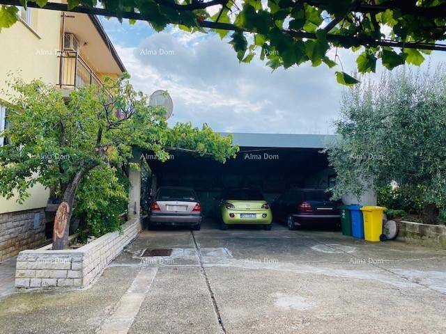 Überdachter Parkplatz für mehrere Fahrzeuge mit angrenzendem Grünbereich und Mülltonnen.