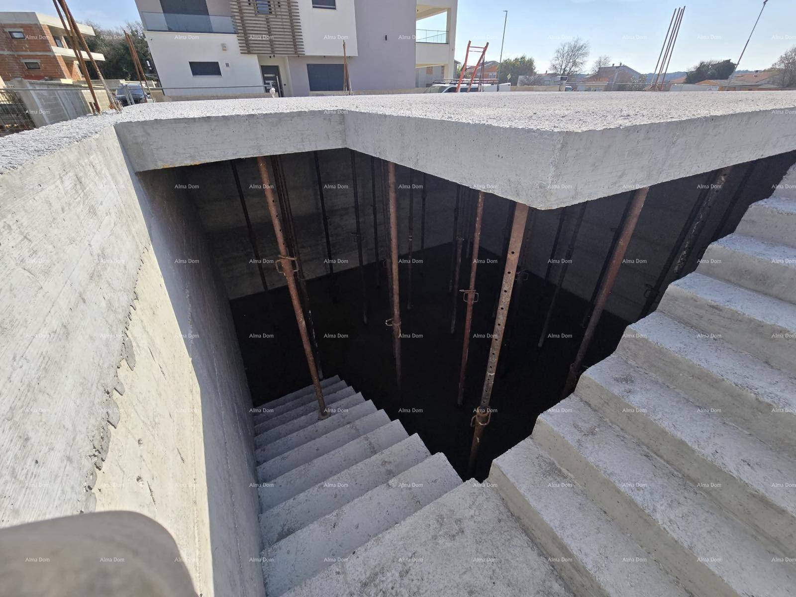 Betonierte Treppe führt hinunter in einen unfertigen Kellerbereich, gestützt von Metallstützen.
