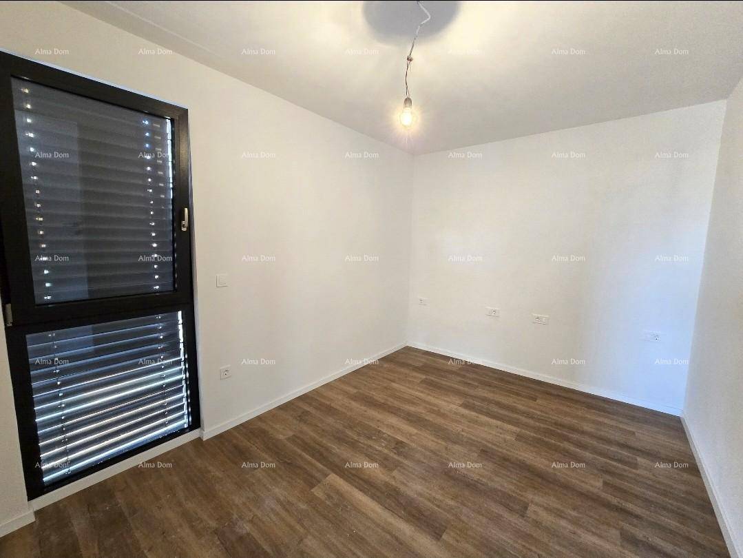 Leeres Schlafzimmer mit Holzboden und einem Fenster mit geschlossenen Jalousien.