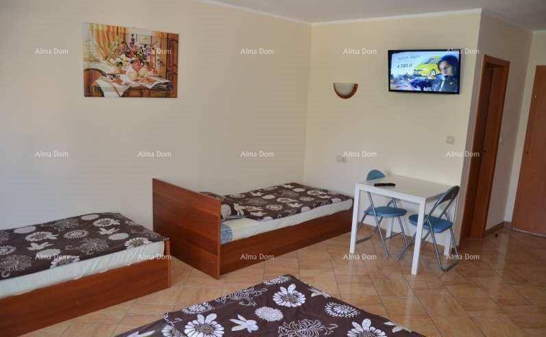 Helles Schlafzimmer mit zwei Einzelbetten, Esstisch und Fernseher an der Wand.