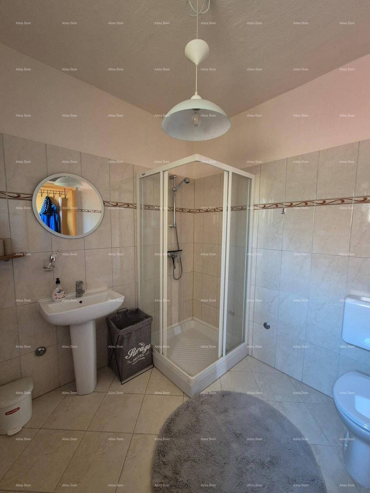 Funktionales Badezimmer mit Eckdusche, Standwaschbecken und WC, gefliest in hellen Farbtönen.