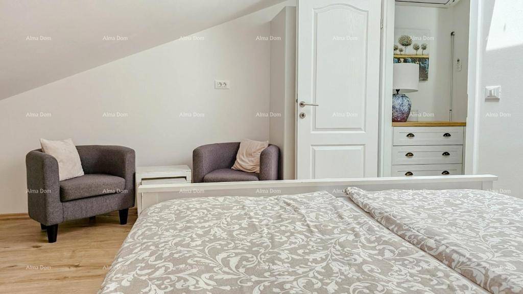 Gemütliches Schlafzimmer im Dachgeschoss mit Holzboden, zwei Sesseln und Blick zum Flur.