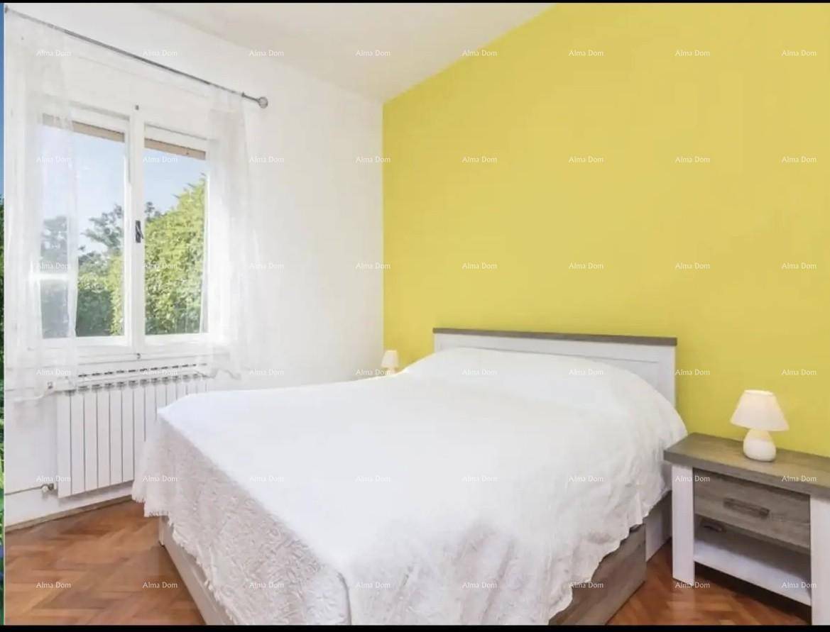 Schlafzimmer mit Doppelbett, gelber Akzentwand und Fenster mit Blick ins Grüne.