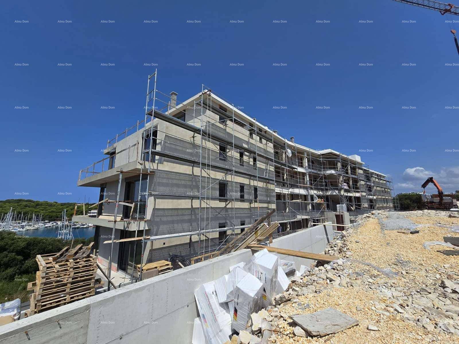 Gebäude im Rohbau mit Gerüst und Blick auf die Küste und den Yachthafen.