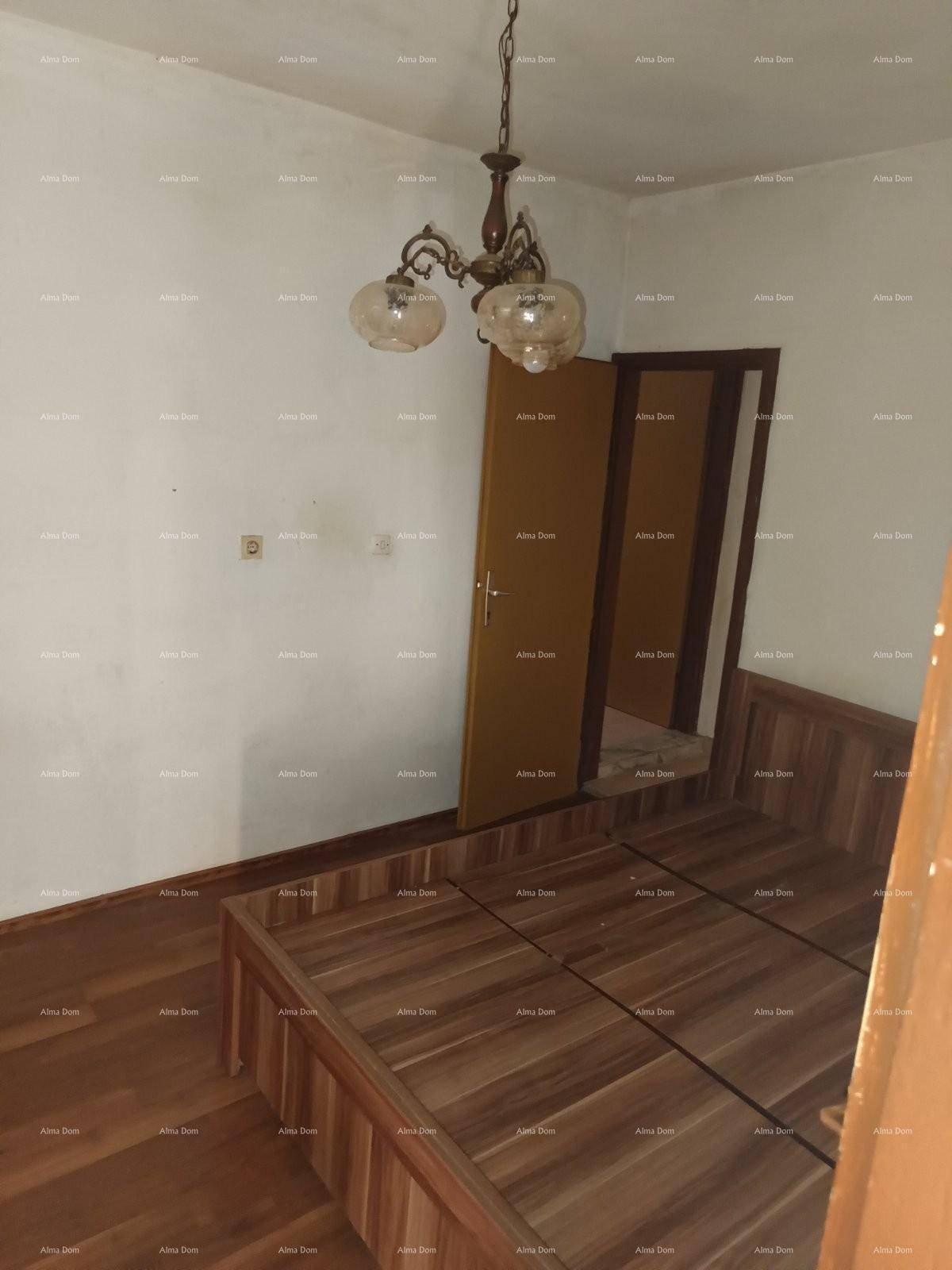 Schlichtes Schlafzimmer mit Holzbettrahmen, Holzboden und klassischer Deckenleuchte.