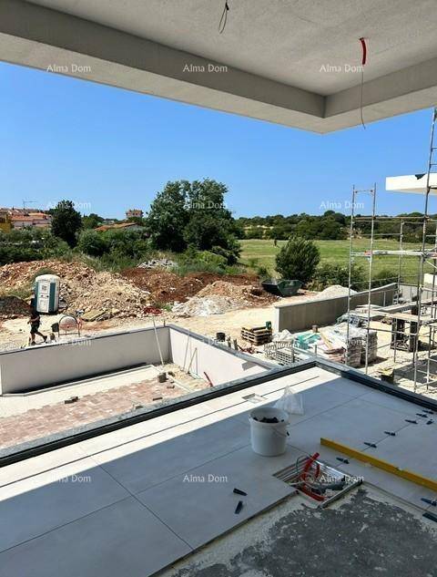 Blick von einer im Bau befindlichen Terrasse auf die Baustelle und die grüne Umgebung.