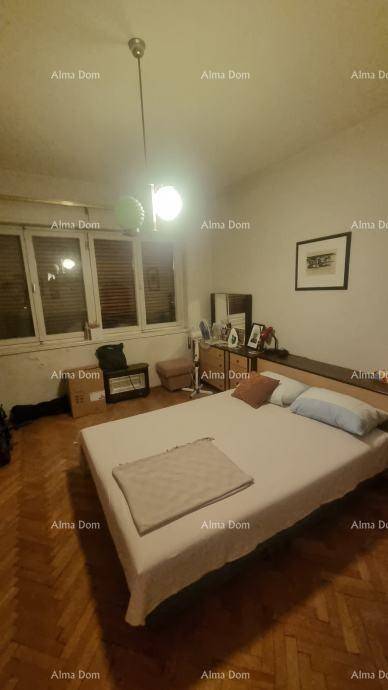 Helles Schlafzimmer mit einem bequemen Bett, einer Kommode und einem großen Fenster für natürliche Beleuchtung.