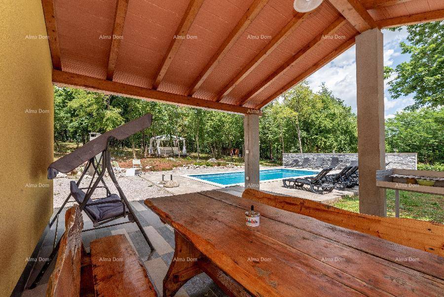 Überdachte Terrasse mit rustikalem Holztisch und Bänken, Blick auf den Poolbereich.