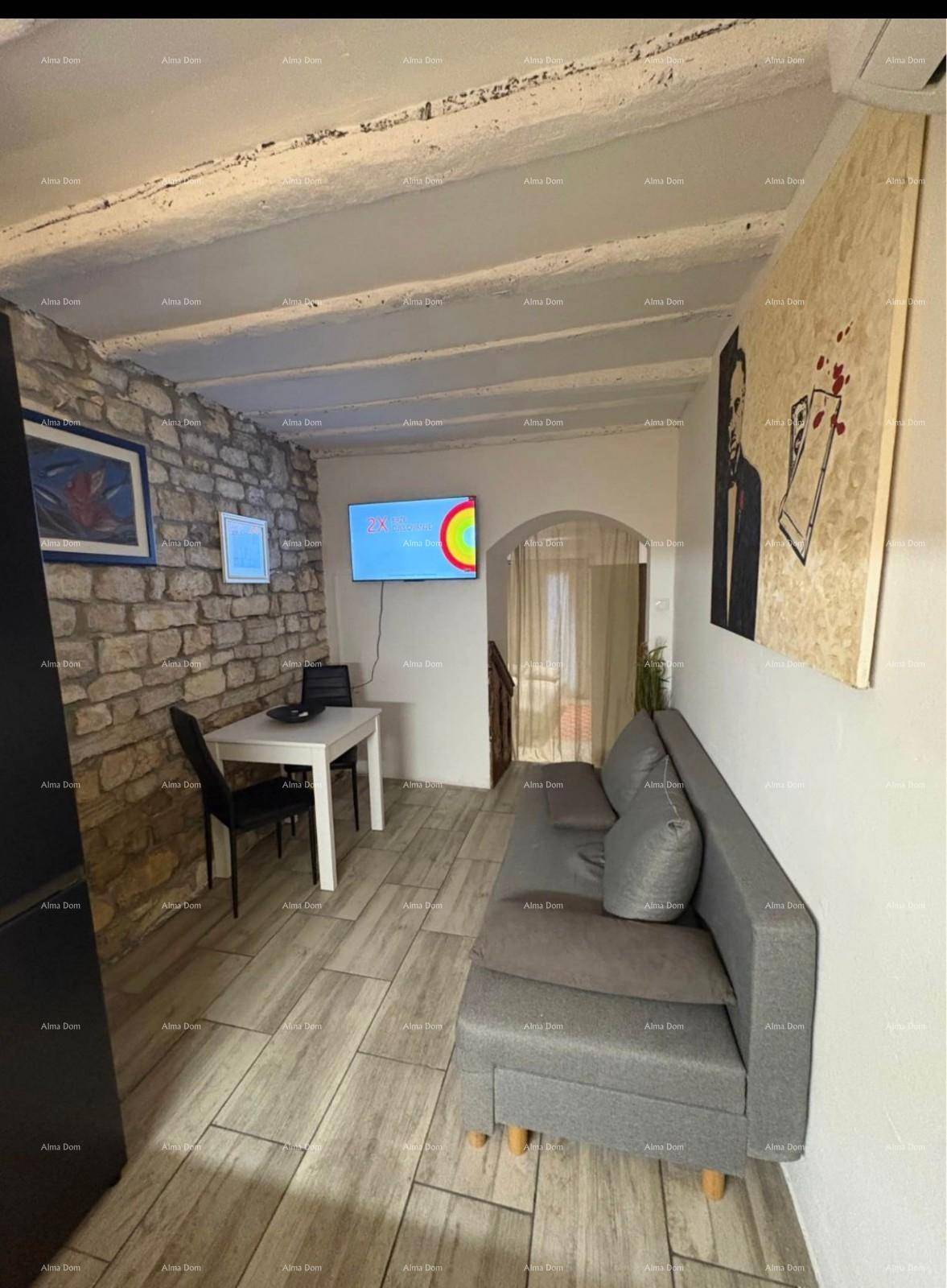 Wohnbereich mit bequemer Couch, Esstisch, Fernseher und rustikalen Holzbalken an der Decke.
