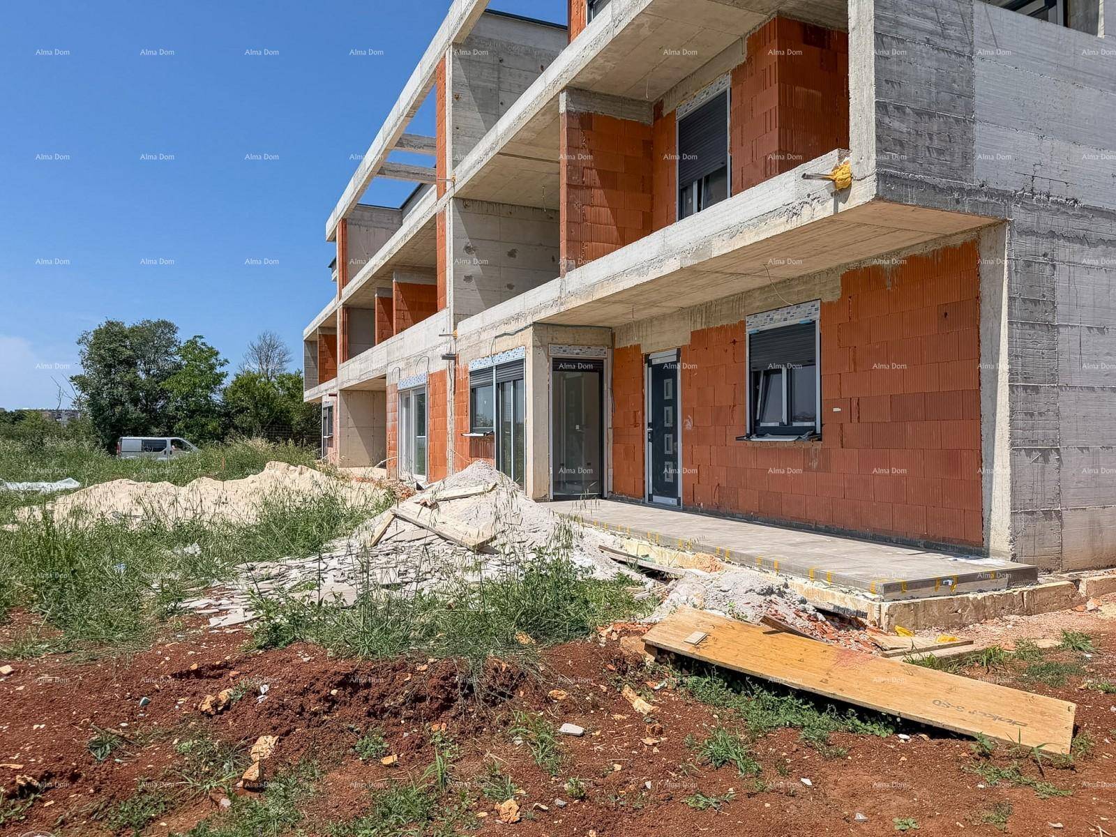 Seitenansicht des Neubaus im Rohbau mit Betonbalkonen und Ziegelwänden.