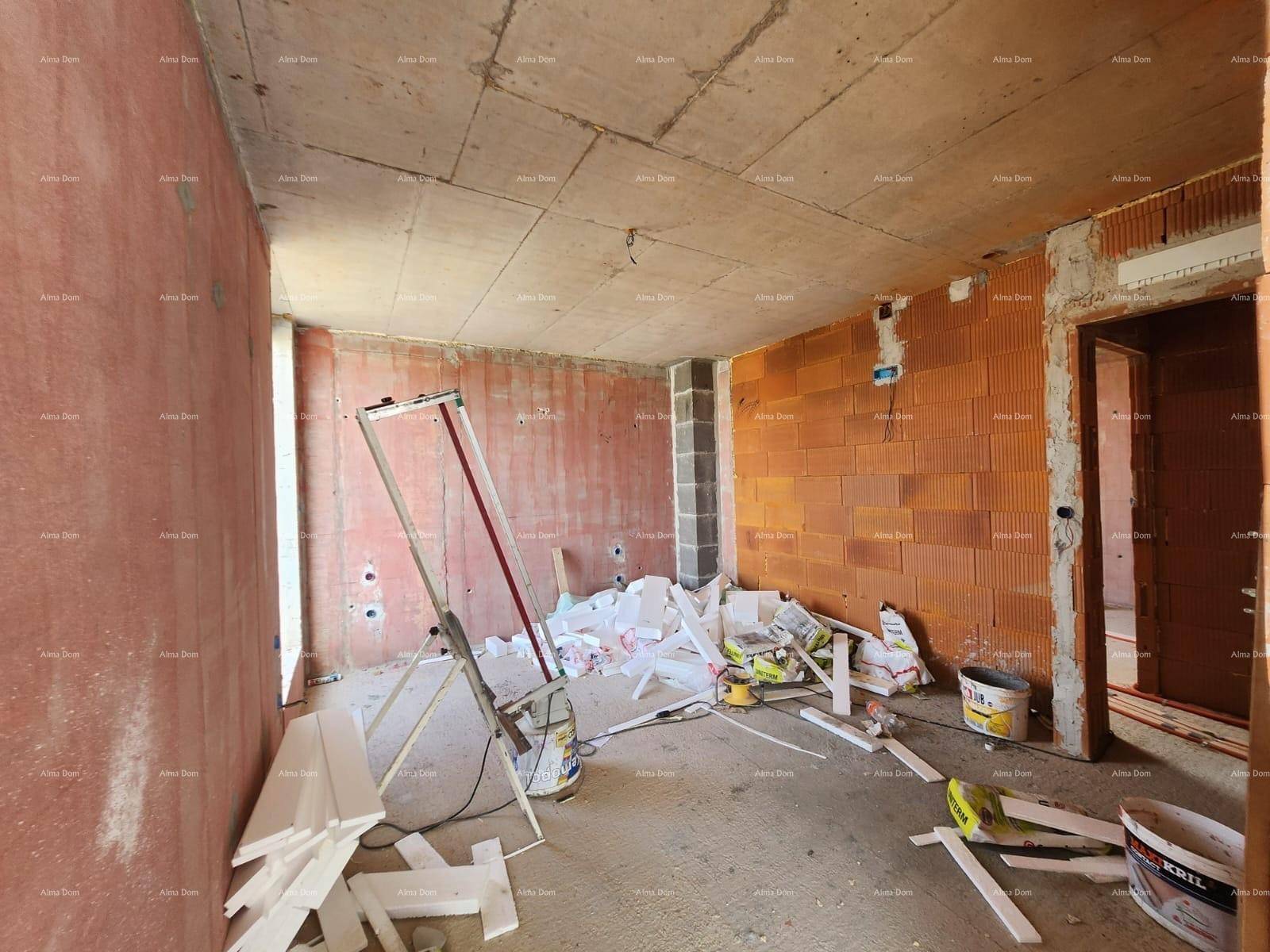 Innenraum im Rohbau mit unverputzten Ziegelwänden, Betonboden und Baumaterialien.
