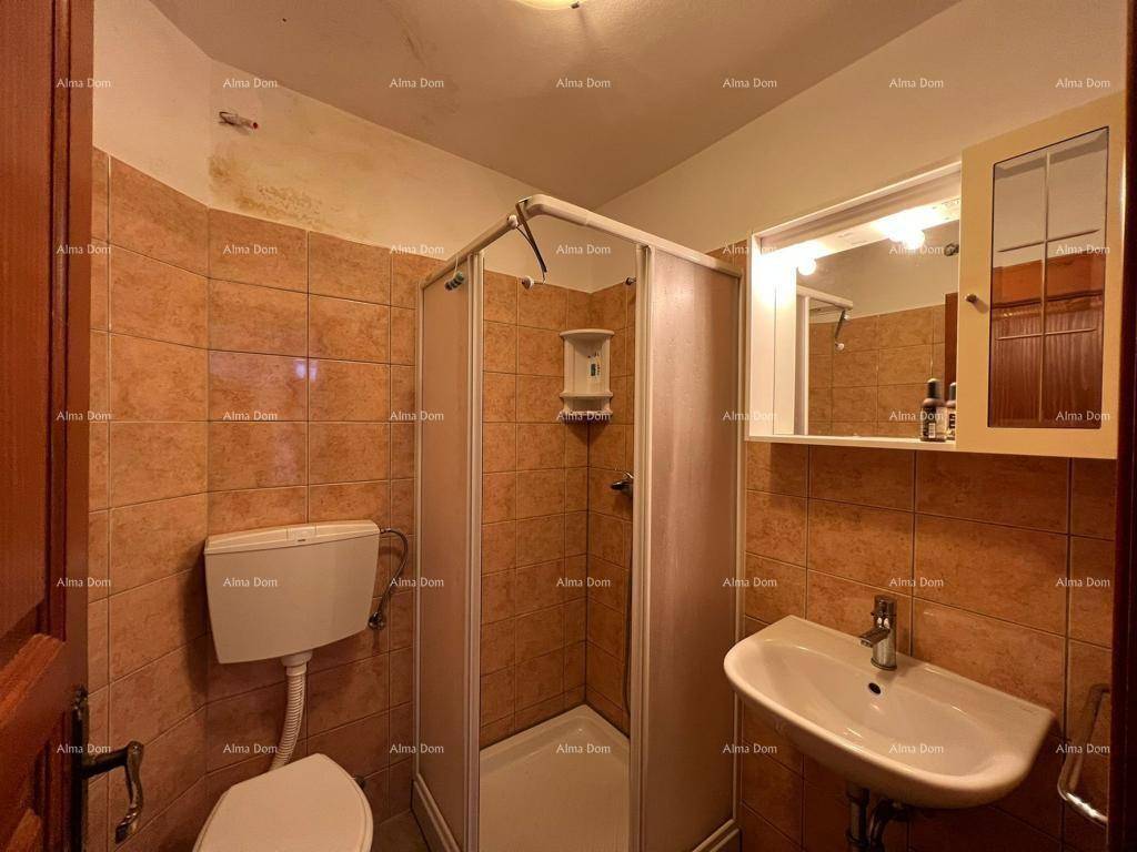 Badezimmer mit Duschkabine, WC und Waschbecken, gefliest in Brauntönen.