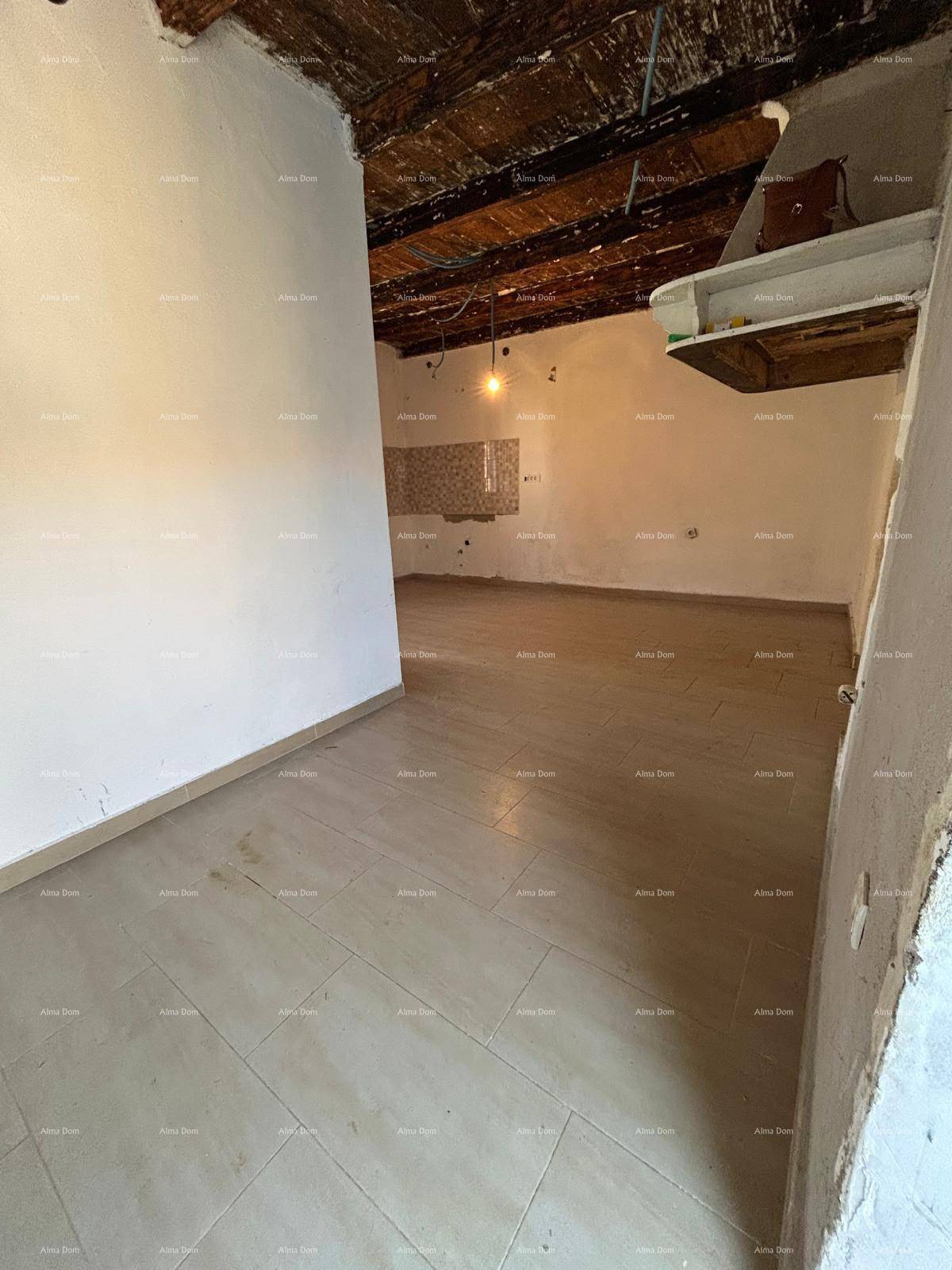 Geräumiger Küchenbereich im Rohbau mit Fliesenboden und sichtbaren Holzbalken an der Decke.