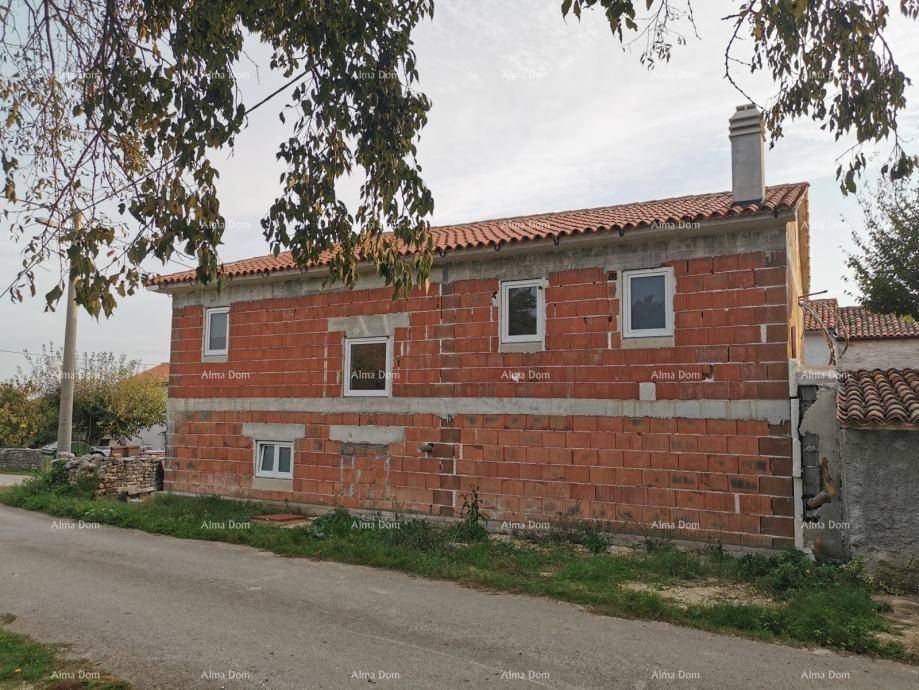 Rohbau eines Hauses mit roten Ziegelwänden, weißen Fenstern und einem Schornstein.