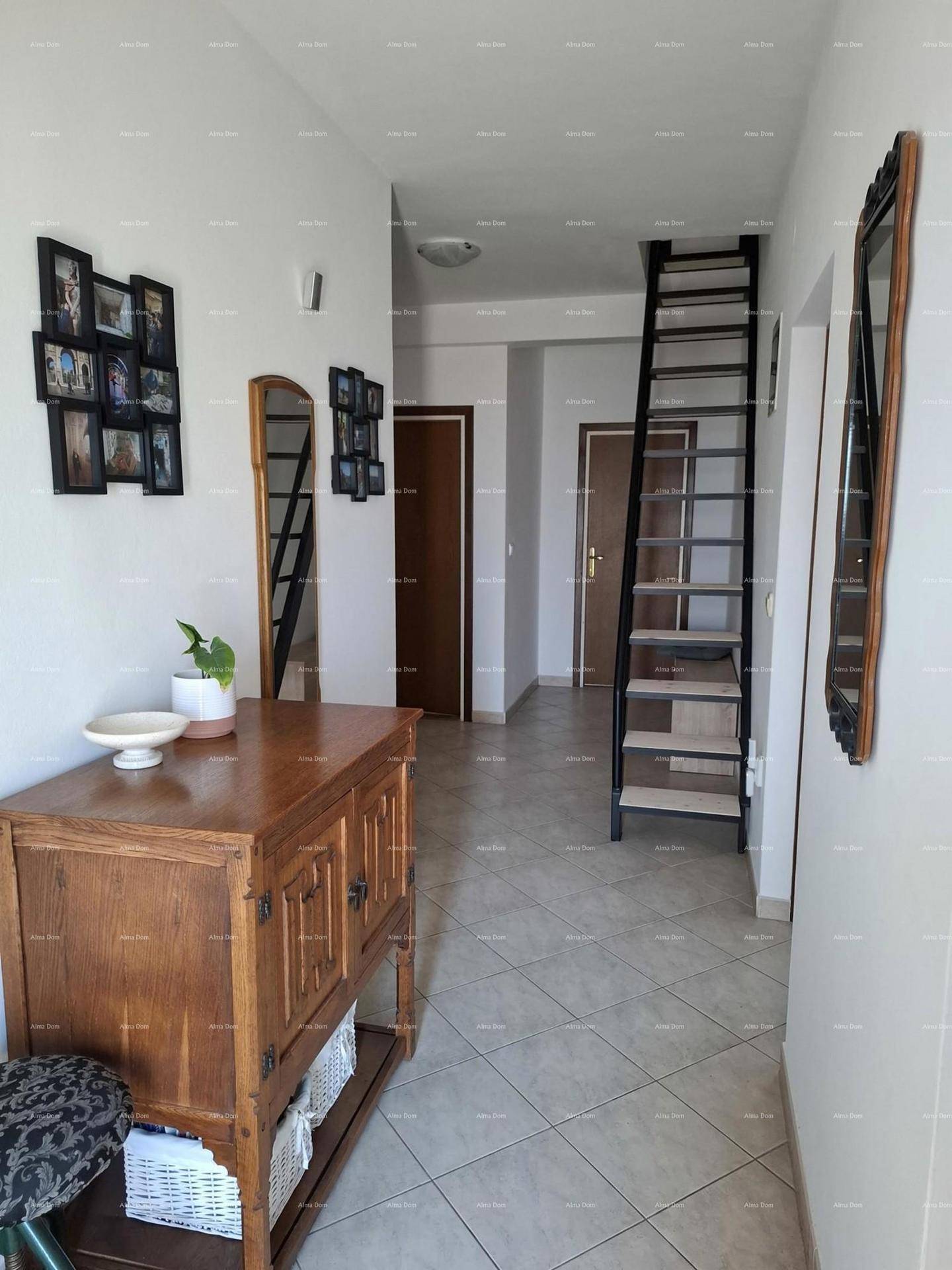 Heller Flur mit Fliesenboden, Holzkommode und schmaler Treppe.