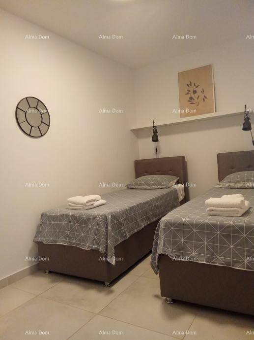 Helles Schlafzimmer mit zwei Einzelbetten, Wanduhr und einfacher Dekoration.