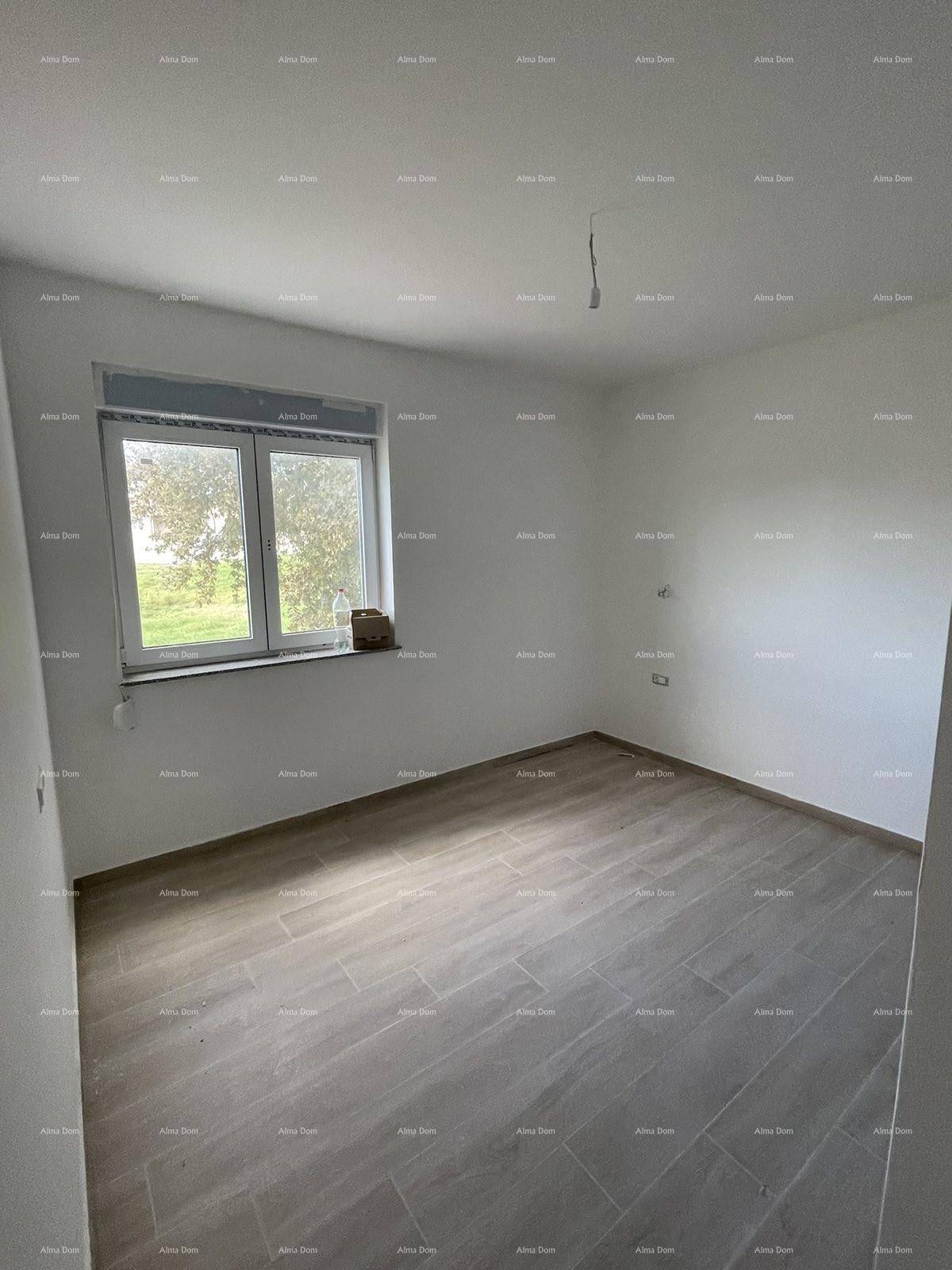 Unfertiges Zimmer mit hellem Fliesenboden, weiß gestrichenen Wänden und Blick ins Grüne.