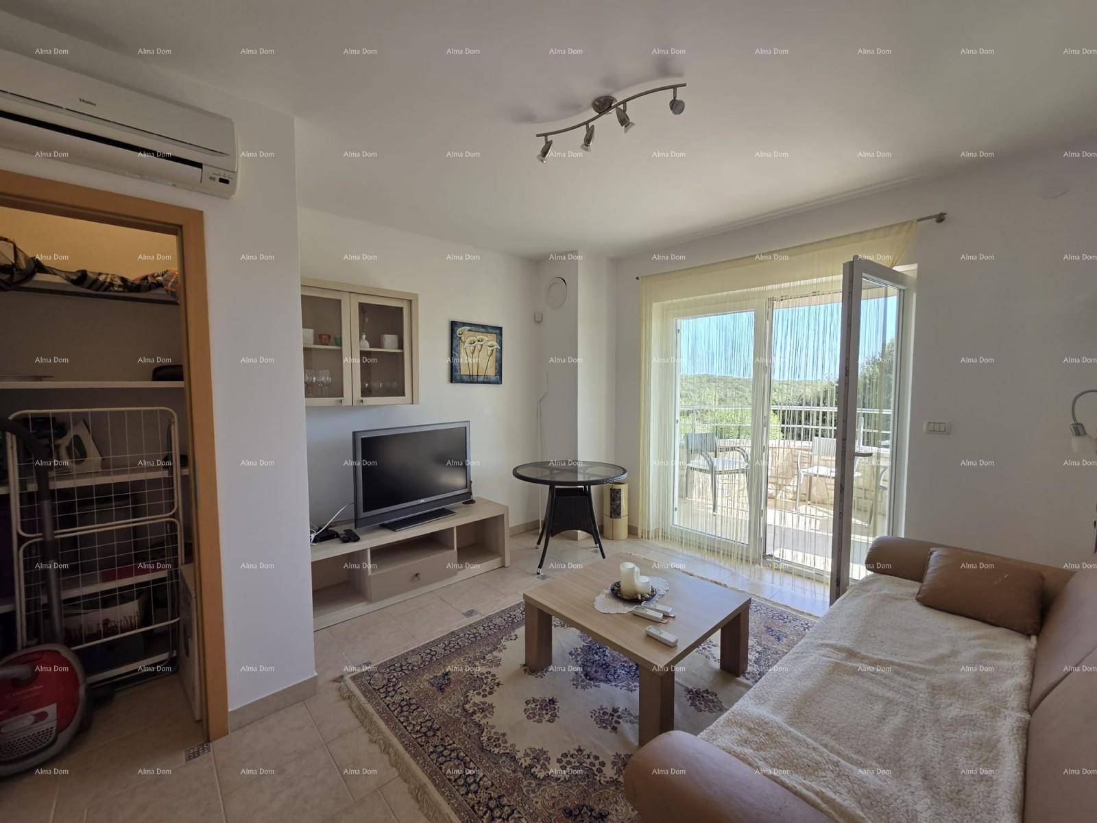 Helles Wohnzimmer mit Sofa, TV, Klimaanlage und Zugang zu einer Außenterrasse mit Meerblick.