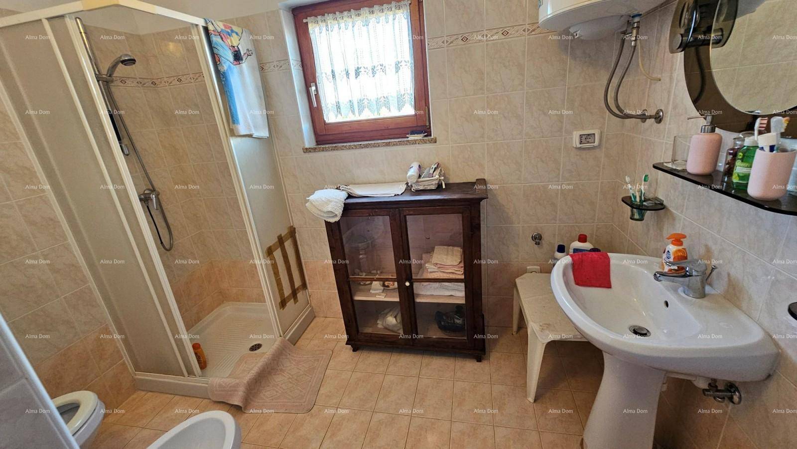 Funktionales Badezimmer mit beigefarbenen Fliesen, Duschkabine und Fenster.