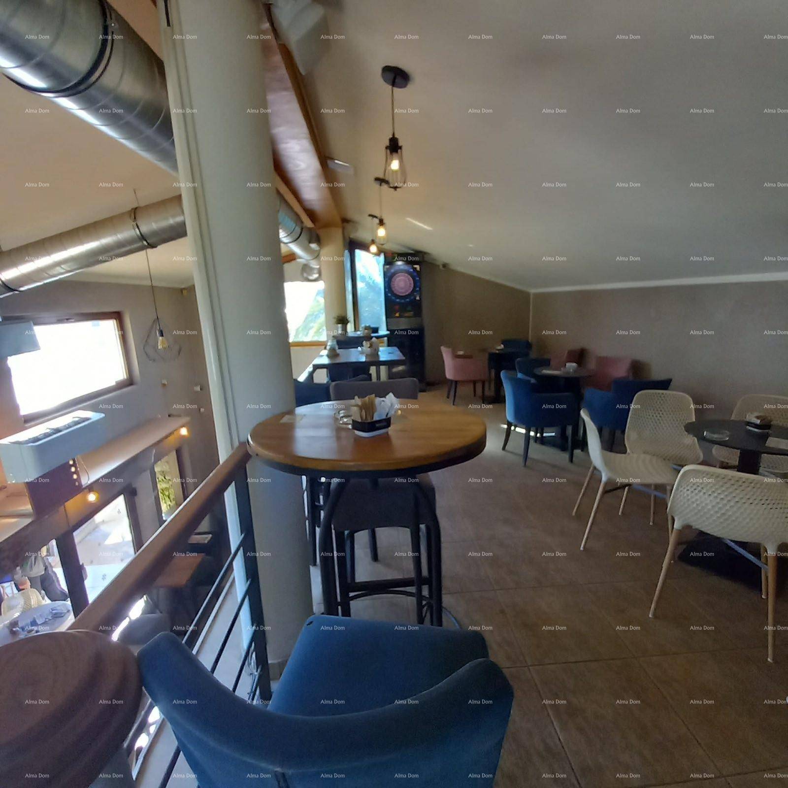 Obergeschoss einer Bar mit verschiedenen Sitzmöglichkeiten, Fliesenboden und Blick nach draußen.