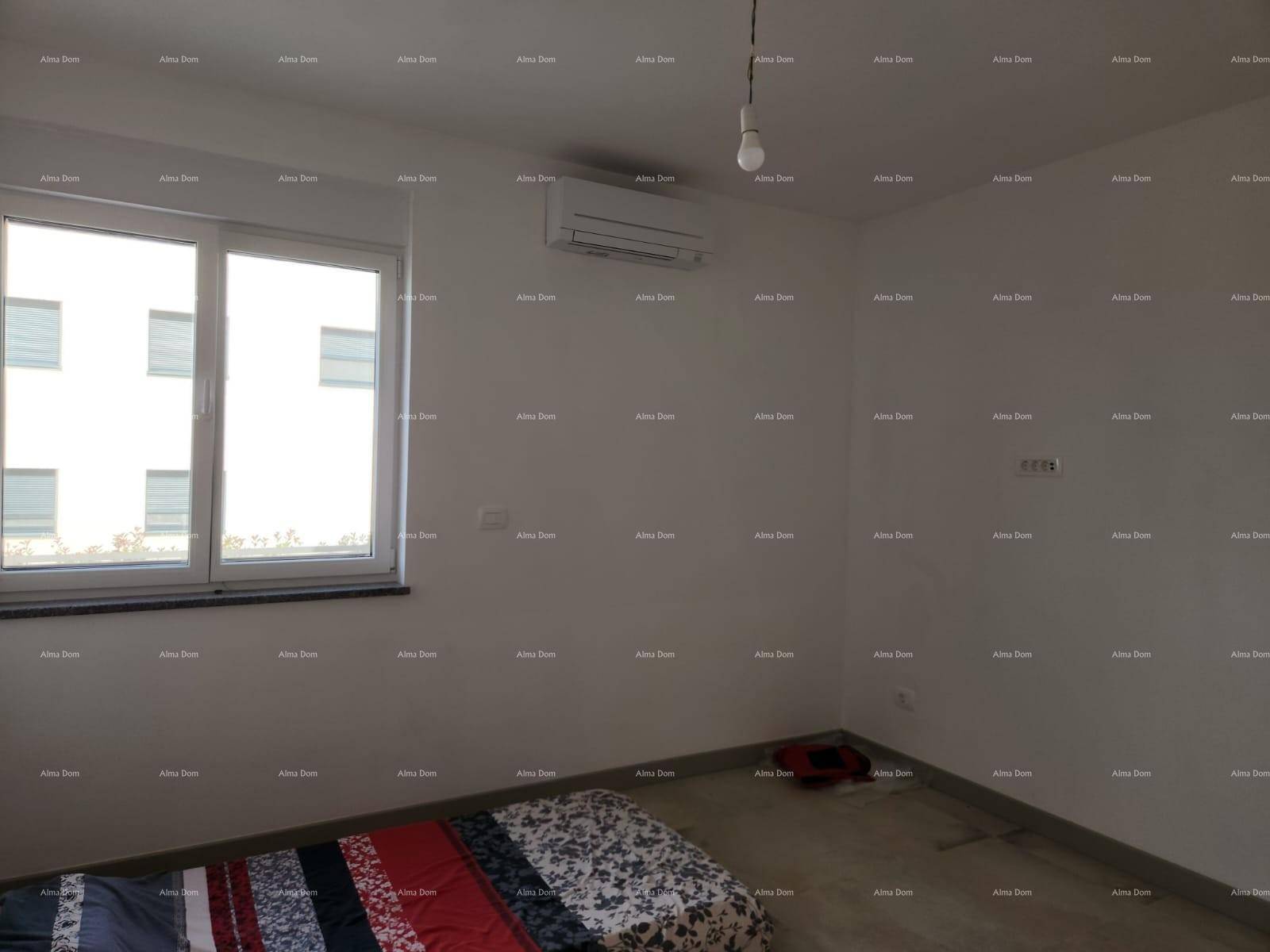 Schlafzimmer mit Klimaanlage, Fenster und einer einfachen Matratze auf dem Boden.