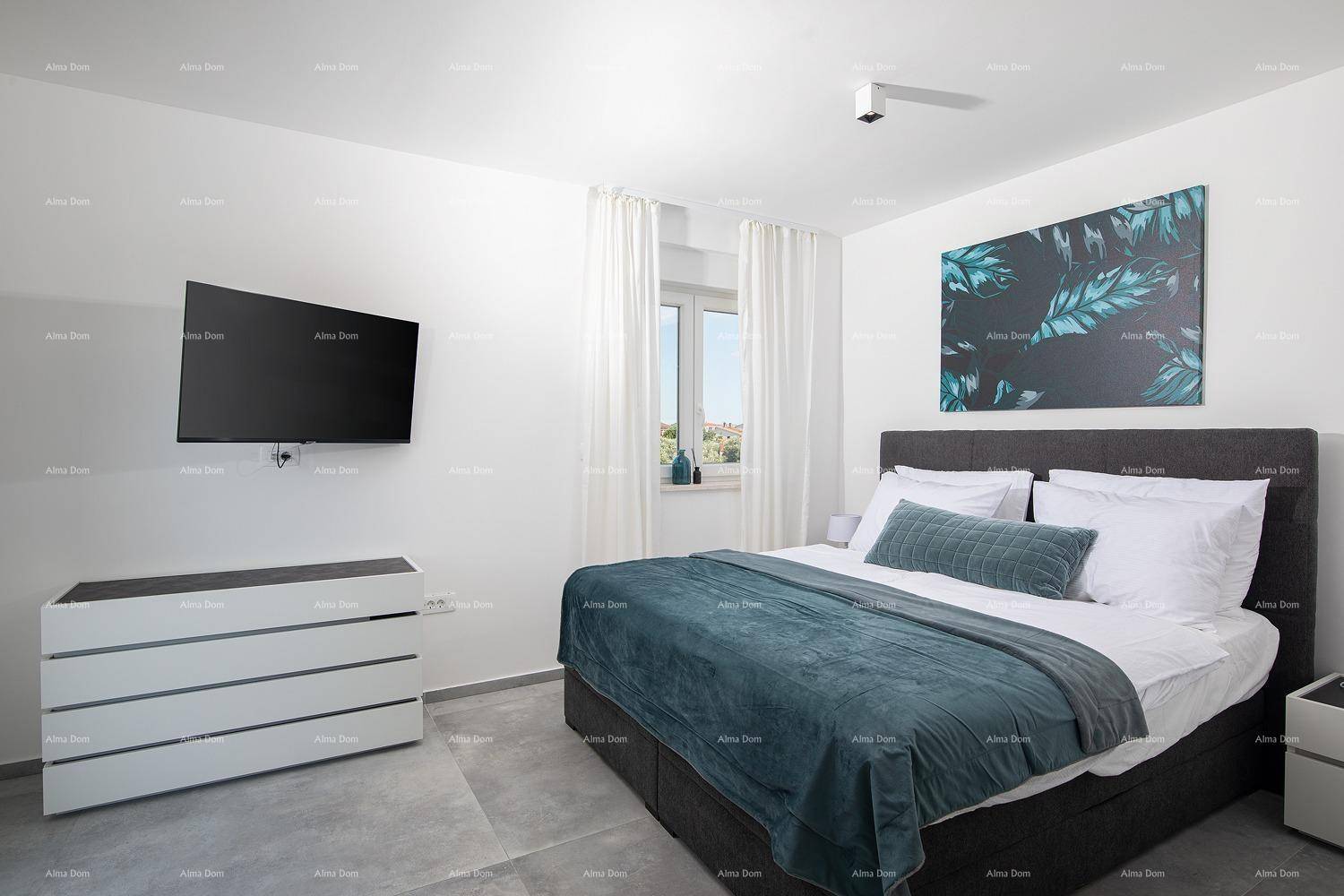 Helles Schlafzimmer mit Doppelbett, Kommode und Fenster mit Blick nach draußen.