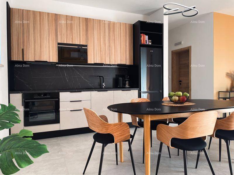 Detailansicht der modernen Einbauküche mit Holzfronten, schwarzen Geräten und Esstisch mit Obstschale.