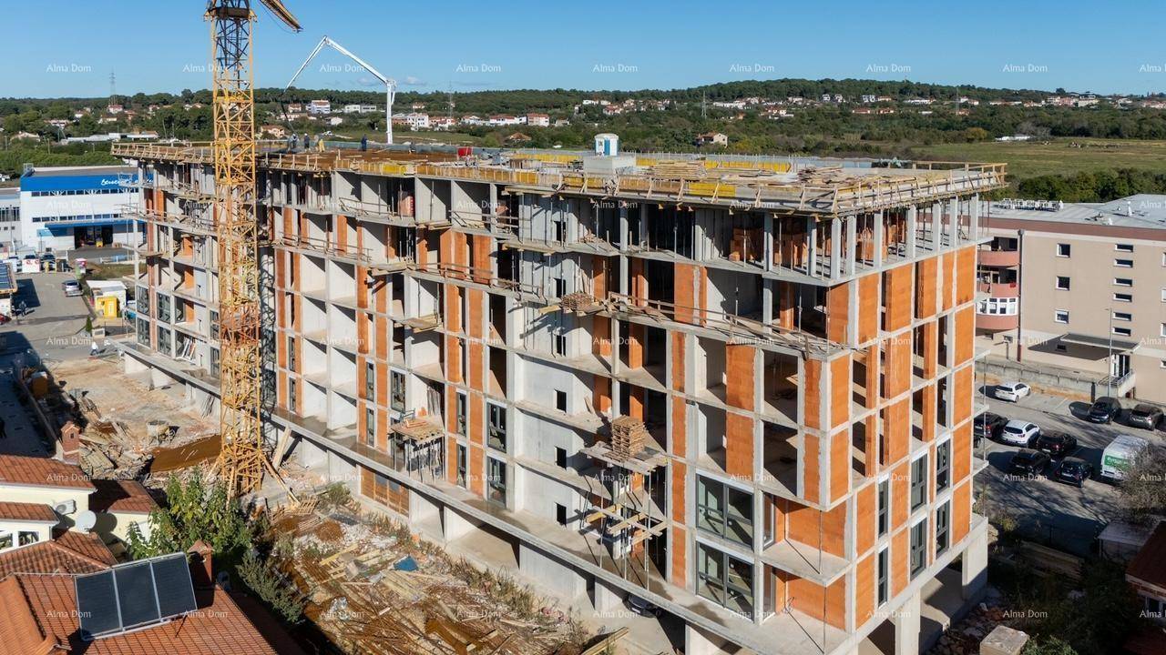 Luftaufnahme einer Baustelle mit einem im Bau befindlichen Gebäude und umliegender Stadtlandschaft.