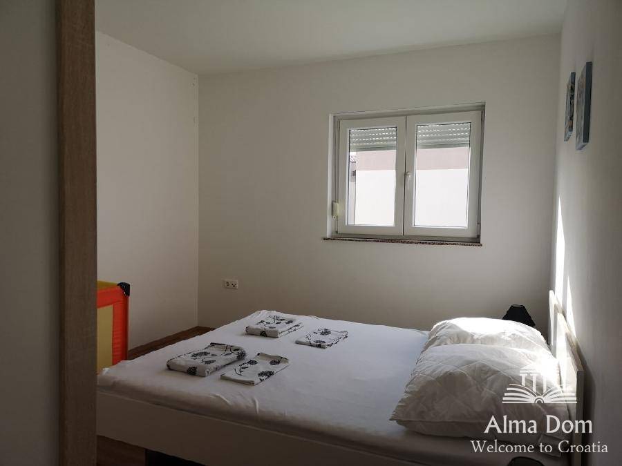 Helles Schlafzimmer mit Doppelbett und Fenster, das viel Tageslicht hereinlässt.