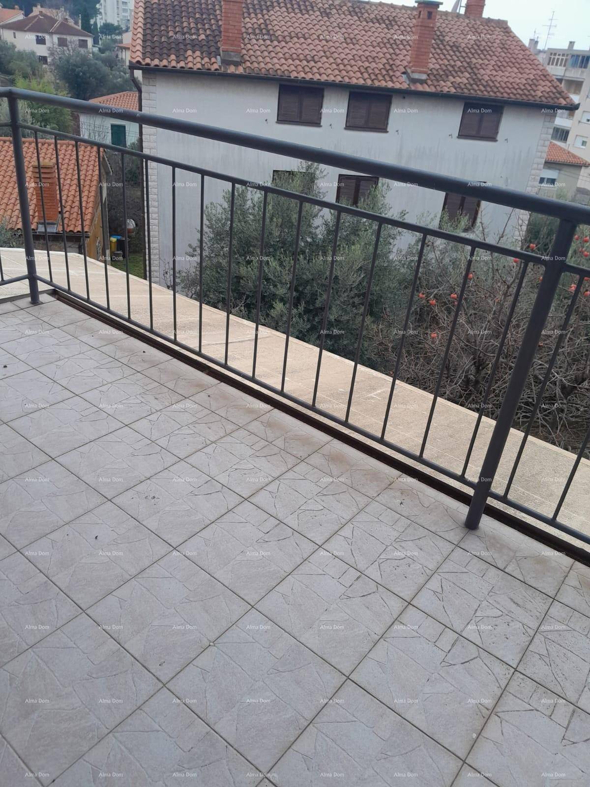Balkon mit Fliesenboden und Metallgeländer, bietet einen Blick auf ein Ziegeldach und Bäume.