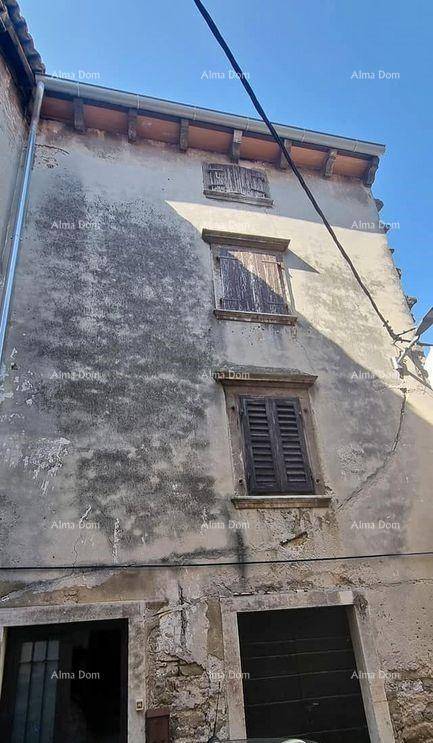 Fassade eines alten Gebäudes mit abgenutztem Putz, Holzfensterläden und zwei Eingängen im Erdgeschoss.