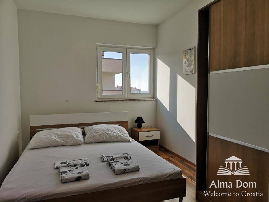Schlafzimmer mit Doppelbett, Holzschrank und Fenster mit Blick auf die Umgebung.