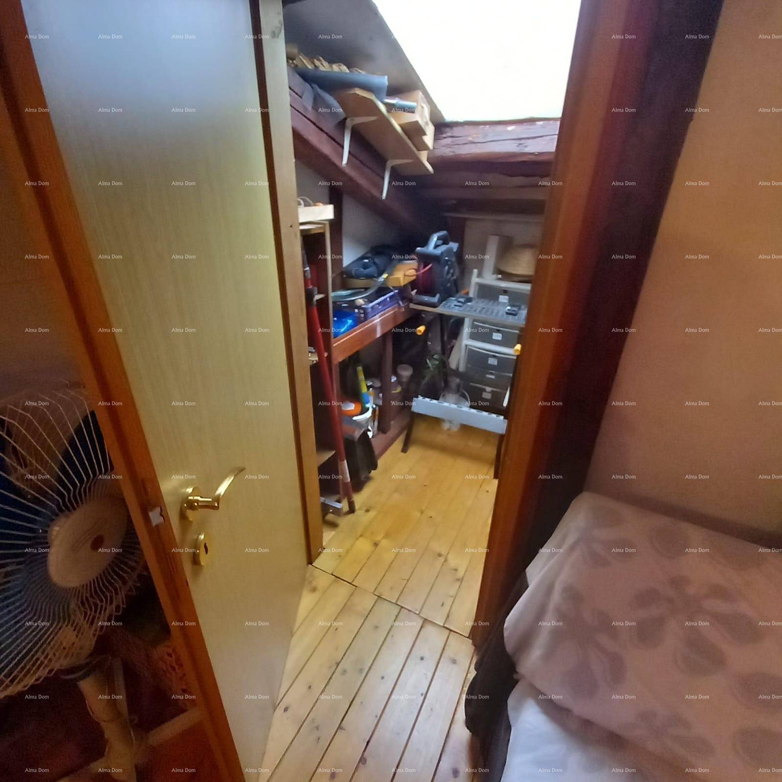 Abstellraum im Dachgeschoss mit Holzboden, Regalen und gelagerten Haushaltsgegenständen.