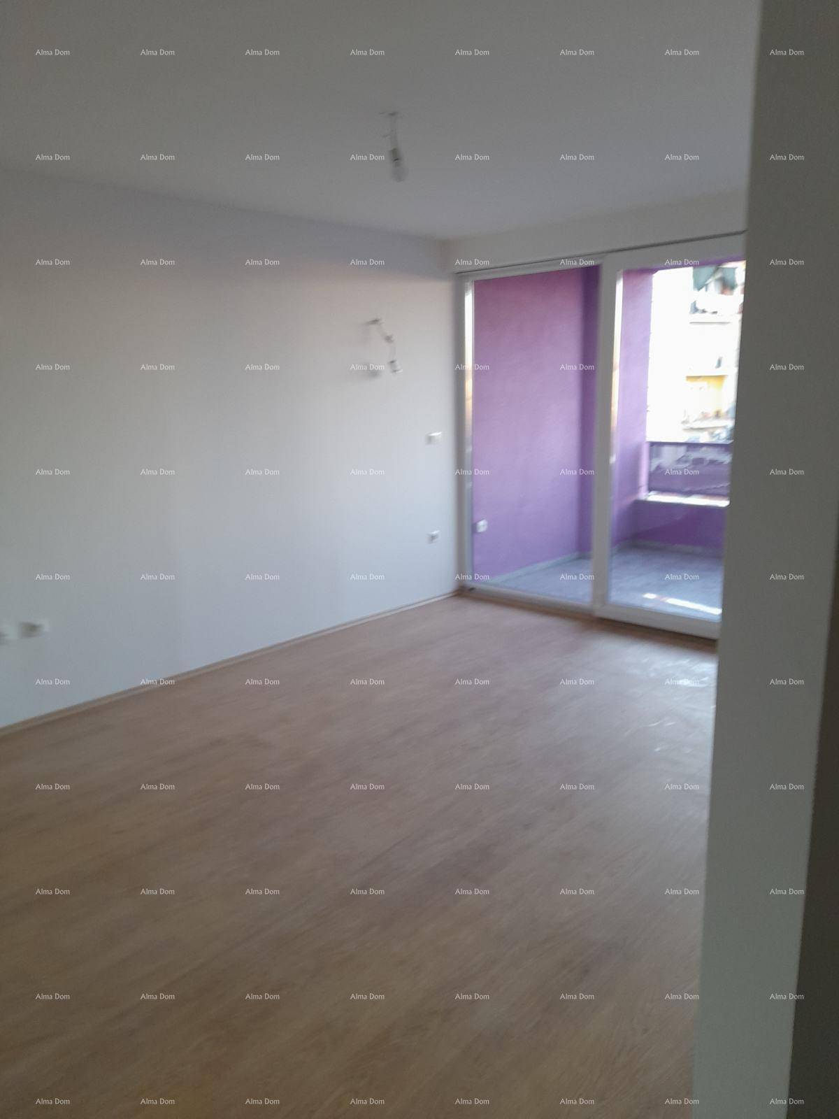 Heller Wohnbereich mit Holzboden und großem Fenster zum lila gestrichenen Balkon.